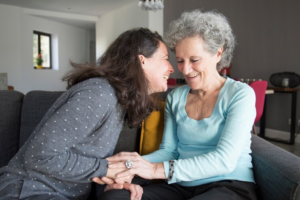 Mulher sorrindo junto a uma parente idosa durante os cuidados