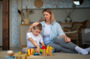 Mãe e filho autista sentados ao chão brincando juntos