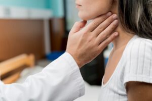 Exame clínico para detecção de linfoma, com médico avaliando linfonodos no pescoço de paciente em ambiente hospitalar.