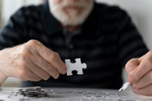 Idoso montando um quebra-cabeça que é uma boa prática para prevenção do Alzheimer