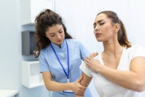 Reumatismo em jovem, doutora cuidando de paciente com dor no ombro