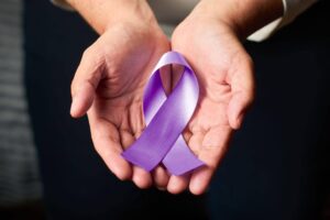 Mão aberta, segurando uma fita roxa símbolo da luta contra a hanseníase.